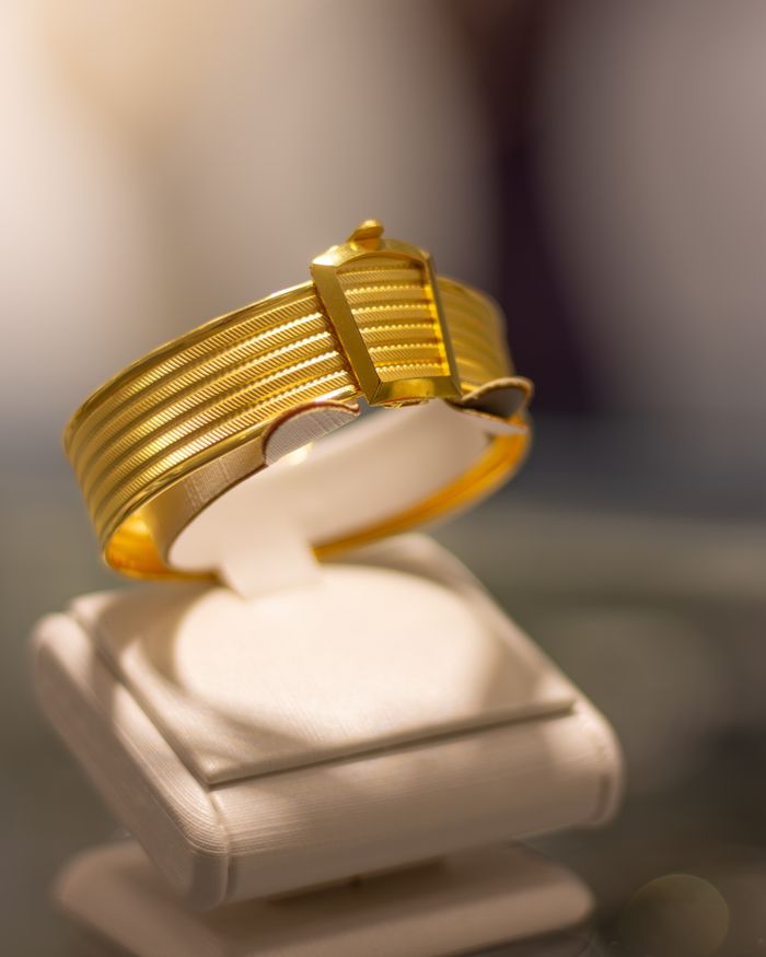 Luxurious gold bracelet elegantly displayed on a white stand, capturing elegance and sophistication.